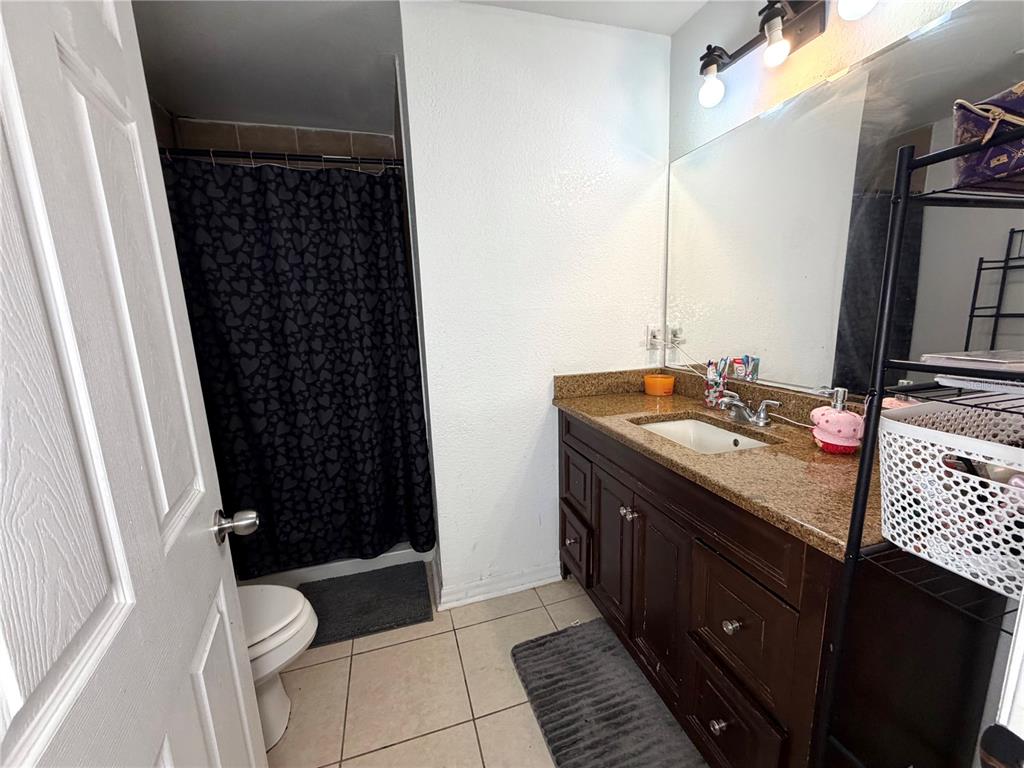 A bathroom features a dark wood vanity, granite countertop, and a shower with a black curtain — 3510 5TH STREET SW, LEHIGH ACRES, FL