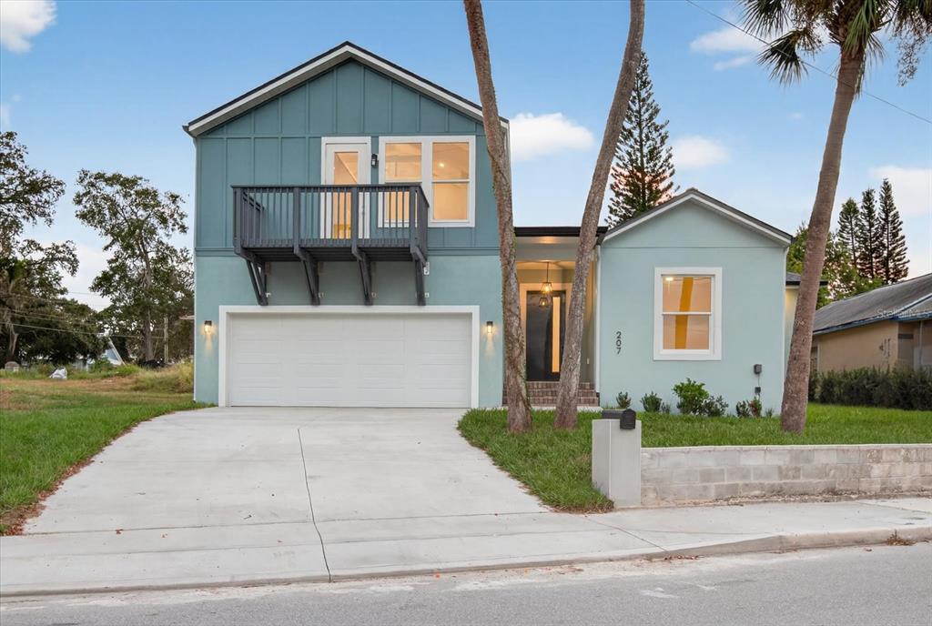 A two-story house with a blue exterior, a front-facing garage, and a second-story balcony — 207 ATHENS STREET, TARPON SPRINGS, FL