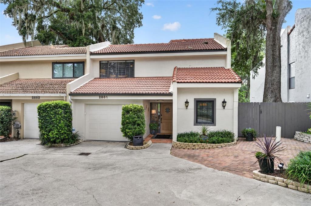 A two-story townhouse with a garage, tiled roof, and a brick-paved entryway — 2881 TEMPLE TRAIL, WINTER PARK, FL