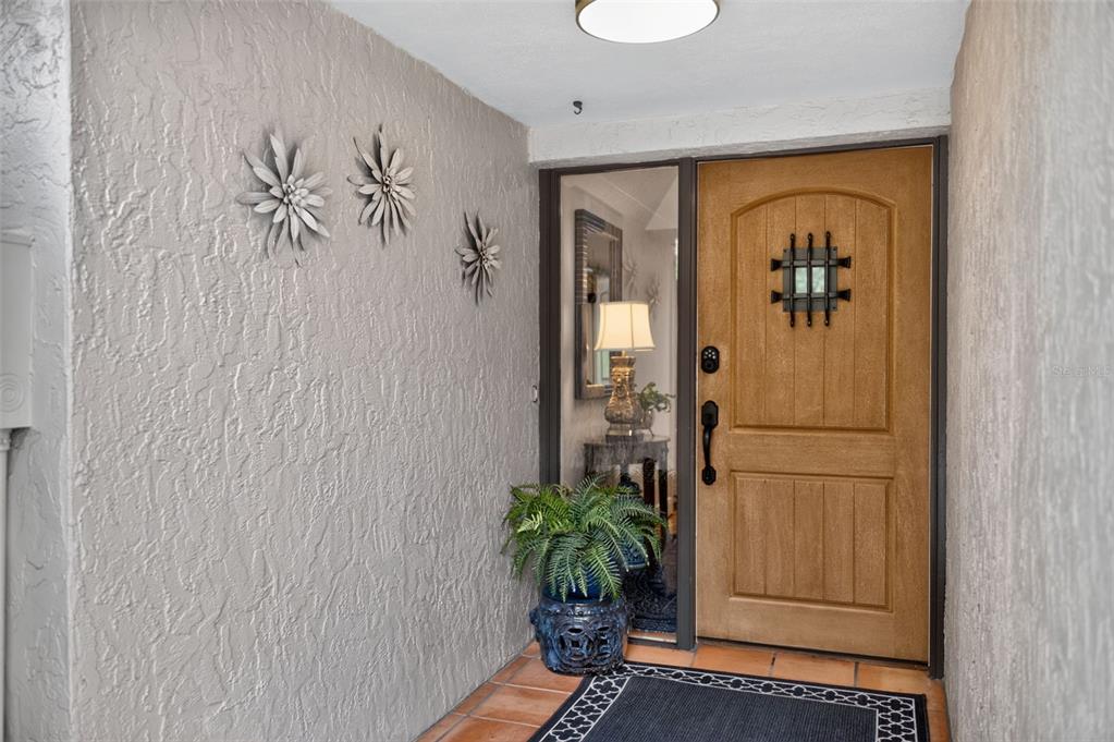 A front entryway features a wooden door with a window, a sidelight, and wall-mounted metal flowers — 2881 TEMPLE TRAIL, WINTER PARK, FL