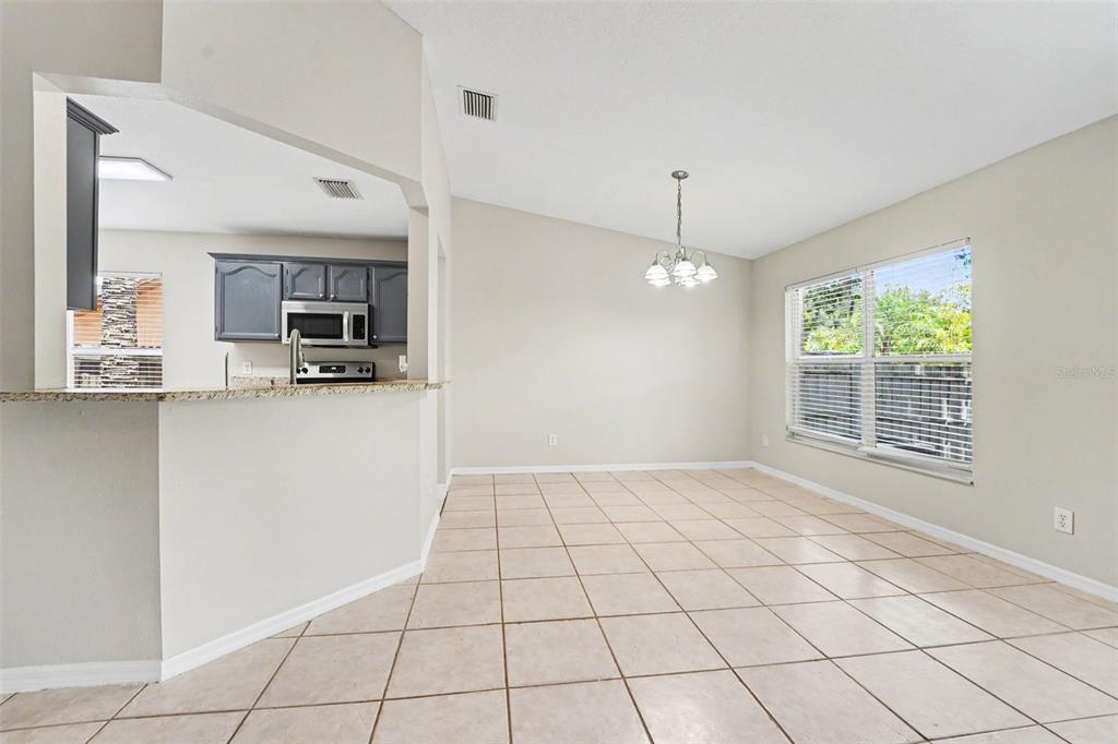 A dining area with beige tile floors, a chandelier, and a view into the kitchen — 7603 SAVANNAH LANE, TAMPA, FL