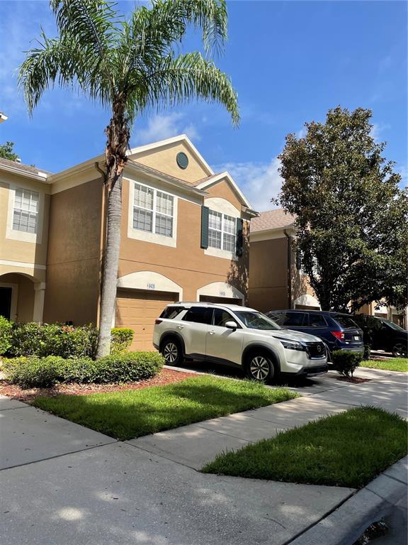 A white SUV is parked in front of a tan two-story townhouse with a palm tree — 8428 SANDY BEACH STREET, TAMPA, FL