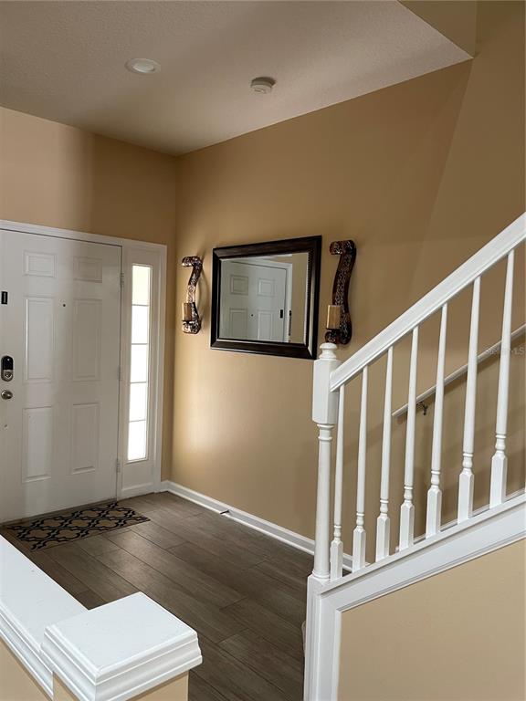 An entryway features wood-look tile flooring, a white front door, and a staircase with white railings — 8428 SANDY BEACH STREET, TAMPA, FL
