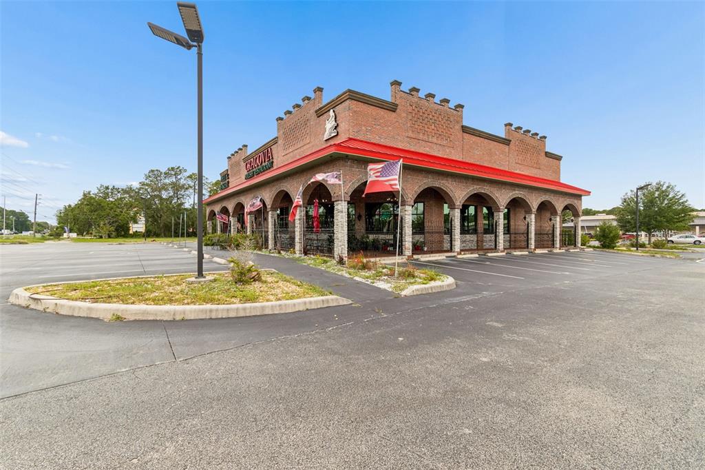 A brick restaurant building with arched covered walkways and a red metal roof — 3007 COMMERCIAL WAY, SPRING HILL, FL
