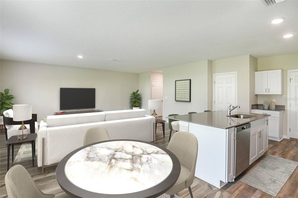 An open-concept living room and kitchen featuring a white sofa, dining table, and island — 1719 VANILLA STREET, HAINES CITY, FL