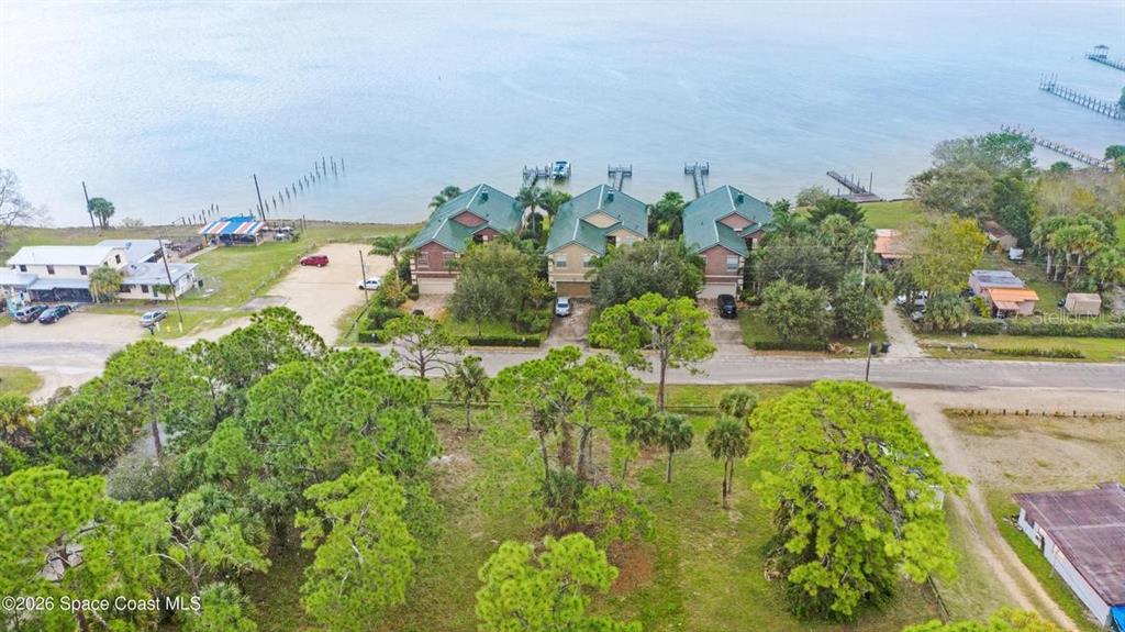 An aerial view shows three waterfront houses with green roofs and private docks — 5416, 5418 & 5420 RIVEREDGE DRIVE, TITUSVILLE, FL