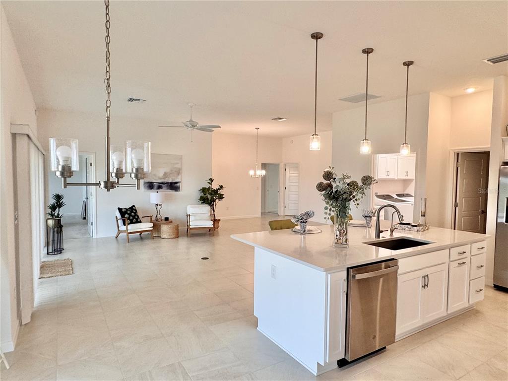 A bright, open-concept kitchen and living area featuring a large white island and tile flooring — 1454 JEREMY CIRCLE, THE VILLAGES, FL