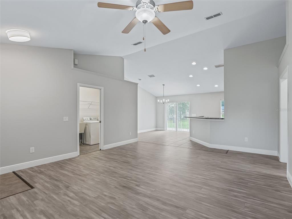 A living area with light gray walls, wood-look flooring, a ceiling fan, and an adjacent laundry room — 5060 PECAN ROAD, OCALA, FL