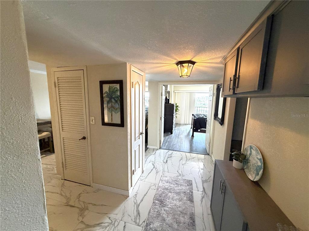 A hallway with marble-patterned tile floors leads to a bedroom with a balcony view — 51 ISLAND WAY UNIT 705, CLEARWATER BEACH, FL