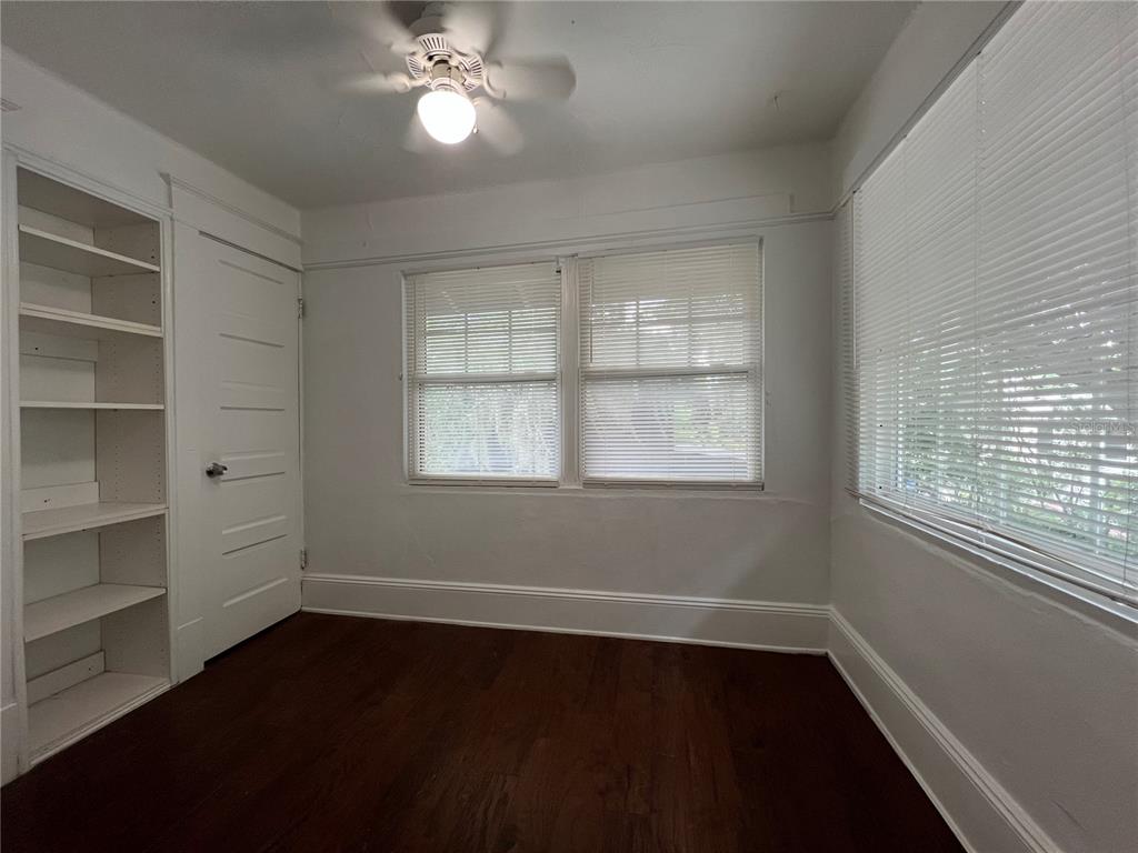 A bedroom features white walls, dark wood flooring, built-in shelving, and two windows with blinds — 510 E JACKSON ST UNIT 5, ORLANDO, FL