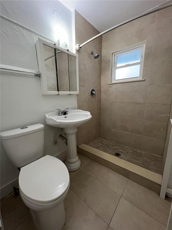 A bathroom features a pedestal sink, a toilet, and a tiled walk-in shower — 510 E JACKSON ST UNIT 5, ORLANDO, FL