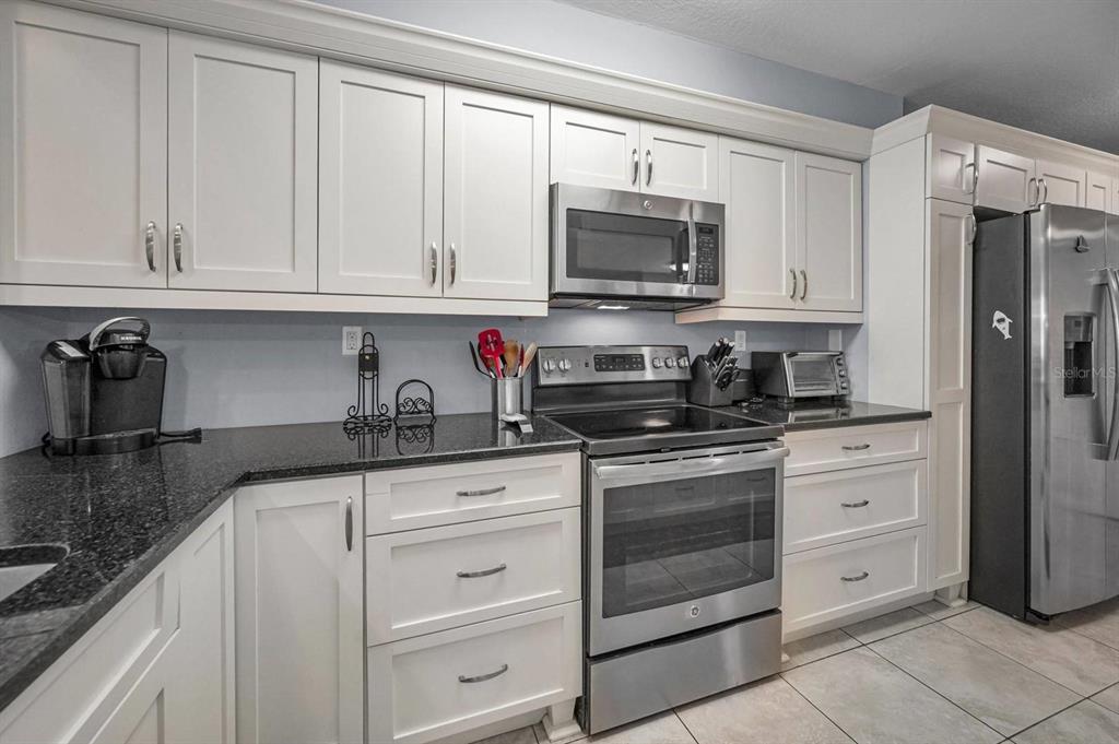 A kitchen with white cabinets, stainless steel appliances, and dark granite countertops — 5901 BAHIA DEL MAR CIRCLE UNIT 223, ST PETERSBURG, FL