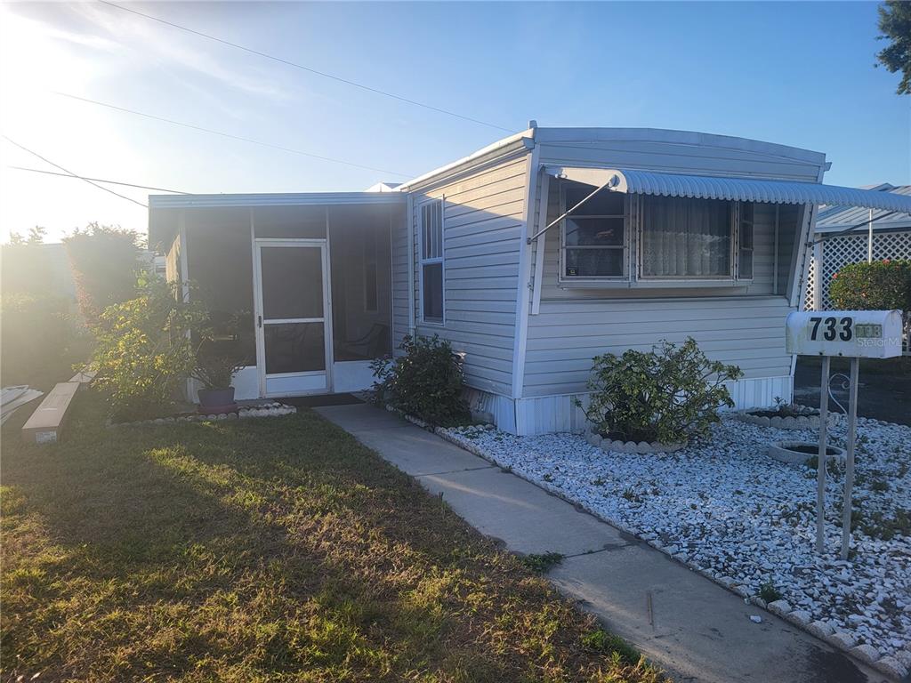 A light-colored mobile home features a screened-in porch and a gravel front yard — 6580 SEMINOLE BOULEVARD UNIT 733, SEMINOLE, FL