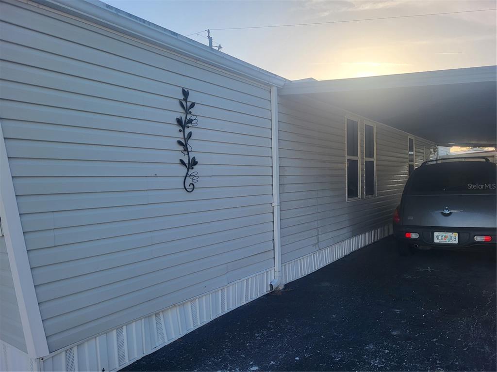 A side view of a mobile home exterior with light gray siding and a carport — 6580 SEMINOLE BOULEVARD UNIT 733, SEMINOLE, FL