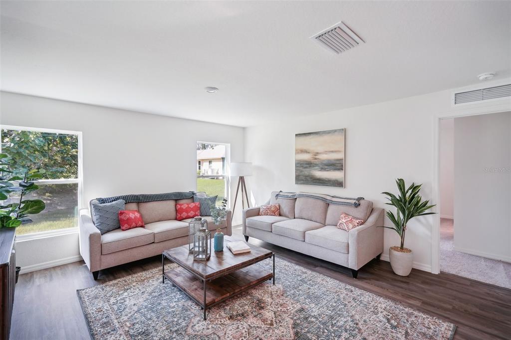 A living room features two beige sofas, a wooden coffee table, and a patterned area rug — 5526 CASTINIA DRIVE, SEBRING, FL