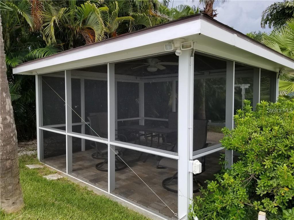 A white-framed screened-in patio with a tiled floor and outdoor furniture sits outdoors — 4000 BELLE VISTA DRIVE, ST PETERSBURG, FL
