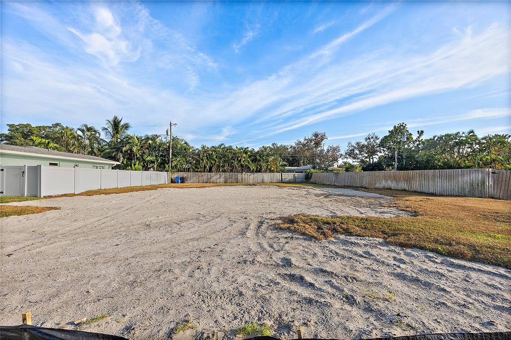 A large, vacant sandy lot is enclosed by a white vinyl fence and wooden fencing — 1235 CORDOVA BOULEVARD NE, ST PETERSBURG, FL