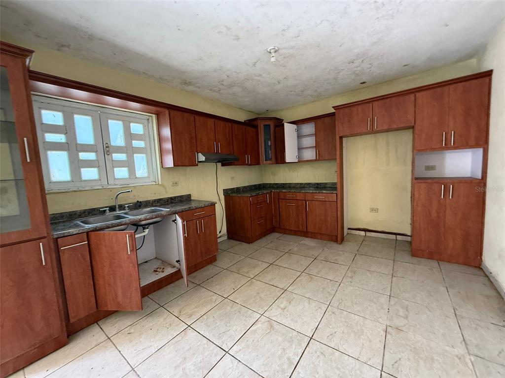 A kitchen with wood cabinets, tiled floors, and a double sink under a window — Bo Anones CARR 108, KM. 19.4, LAS MARIAS, PR