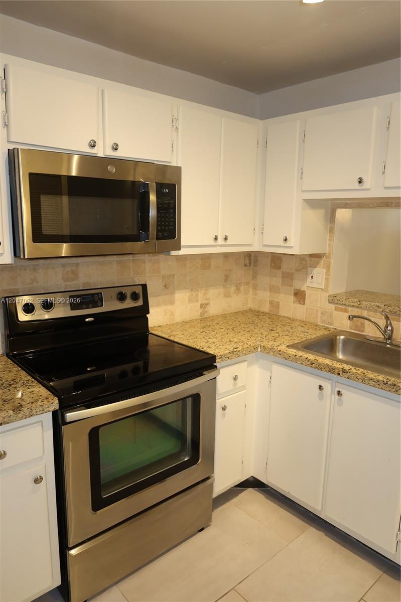 A kitchen features white cabinets, granite countertops, a stainless steel stove, and a microwave — 10835 SW 112th Ave # 113, Miami FL 33176, MIAMI, FL