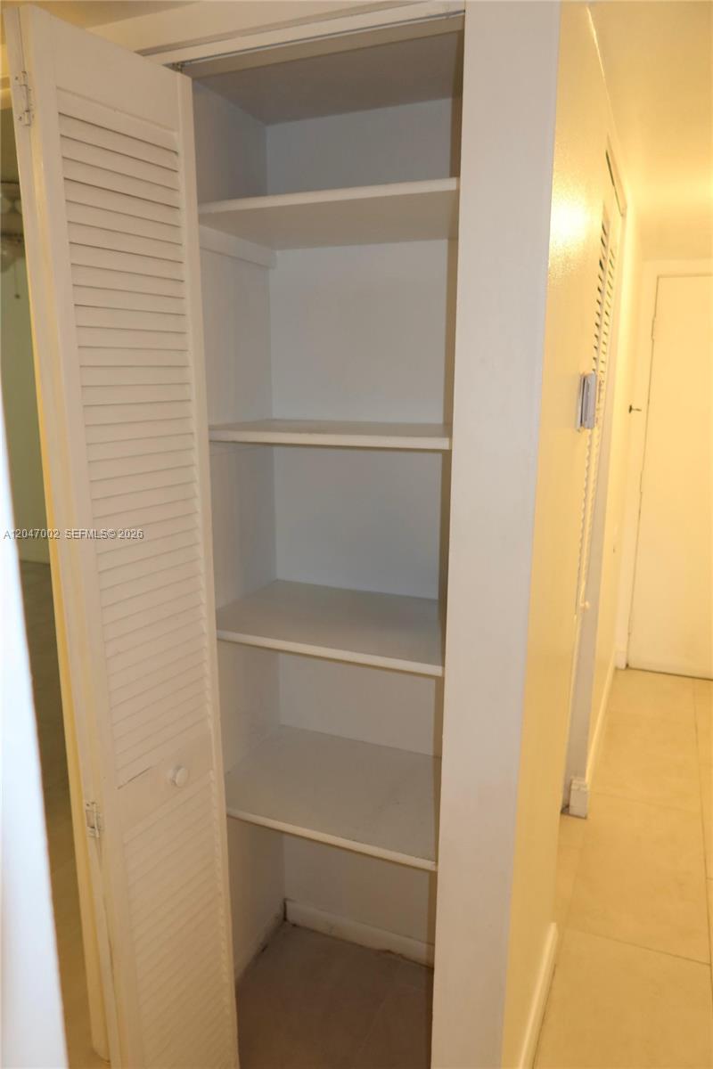 An open white louvered door reveals a closet with four interior shelves — 10835 SW 112th Ave # 113, Miami FL 33176, MIAMI, FL