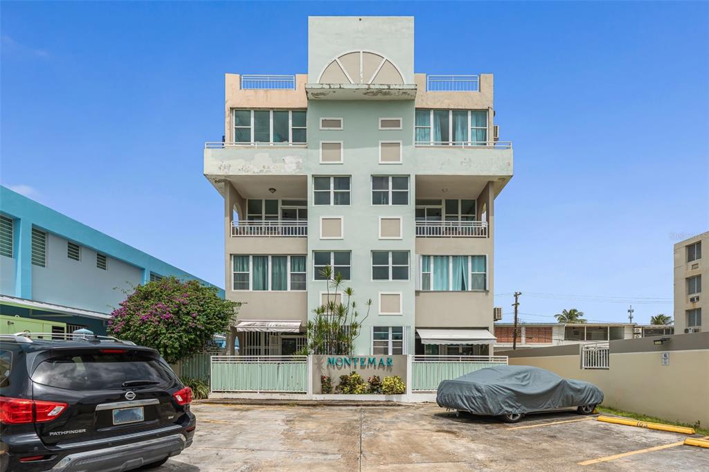 A multi-story apartment building with a pale green facade and a parking lot in front — Cond. Montemar 101, OCEAN DRIVE UNIT 101, LUQUILLO, PR
