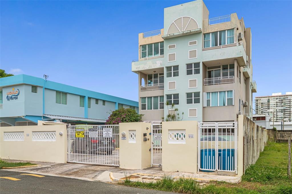A multi-story apartment building with a gated entrance and a neighboring structure labeled Luquillo Waves — Cond. Montemar 101, OCEAN DRIVE UNIT 101, LUQUILLO, PR