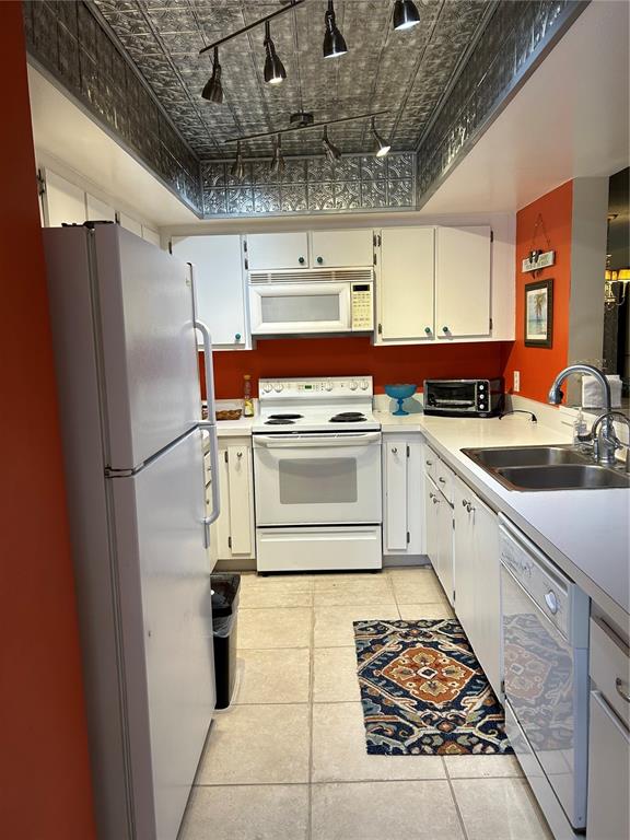 A kitchen with white cabinets, orange walls, a metal ceiling, and white appliances — 6102 7TH AVENUE W UNIT 6102, BRADENTON, FL
