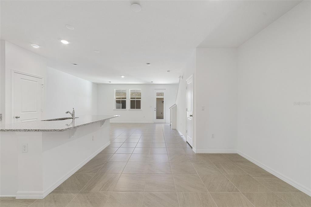 An open-concept kitchen and living area features light tile flooring and white walls — 684 LOLA LANE, OVIEDO, FL