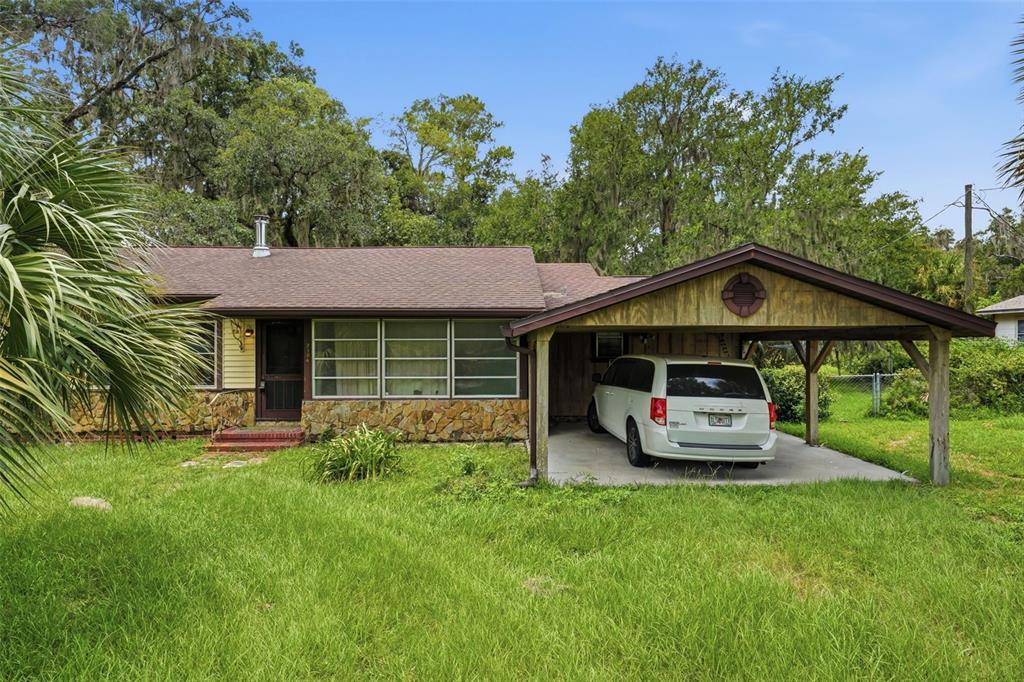 A single-story house with a stone facade, yellow siding, and an attached carport with a van — 2104 SE LAKE WEIR AVENUE, OCALA, FL