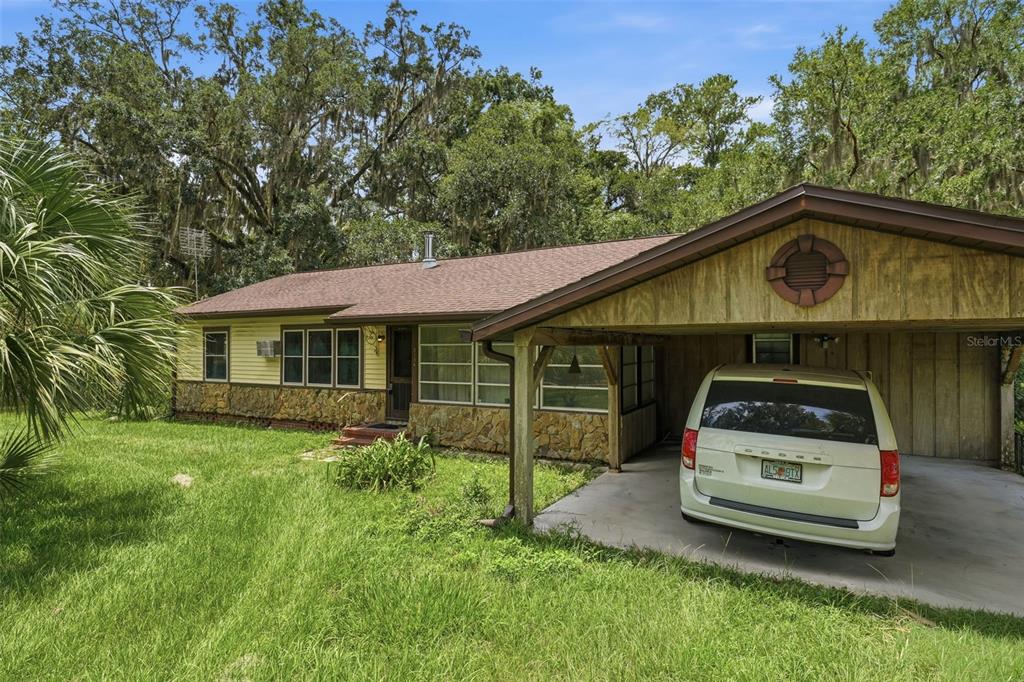 A single-story house with yellow siding, stone accents, and a carport containing a white minivan — 2104 SE LAKE WEIR AVENUE, OCALA, FL