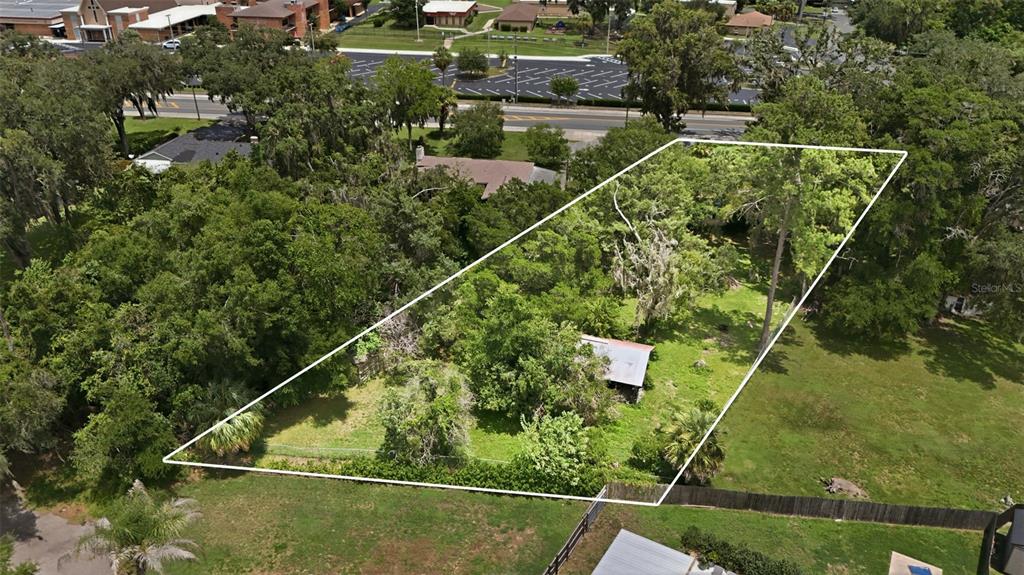 An aerial view shows a wooded, rectangular lot with a small structure and white boundary lines — 2104 SE LAKE WEIR AVENUE, OCALA, FL