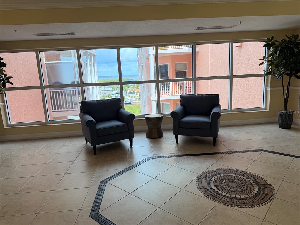 Two armchairs and a small table sit before a large window overlooking a coastal view — 4516 SEAGULL DRIVE UNIT 515, NEW PORT RICHEY, FL
