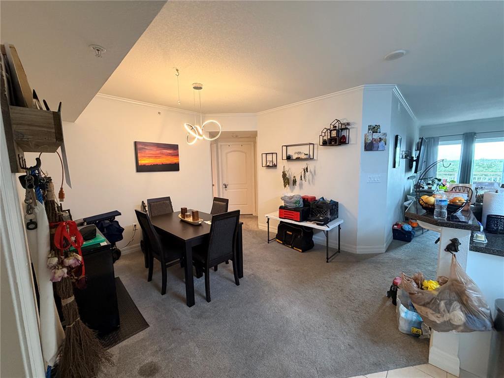 A dining area with a modern light fixture, carpeted flooring, and an adjacent kitchen counter — 4516 SEAGULL DRIVE UNIT 515, NEW PORT RICHEY, FL