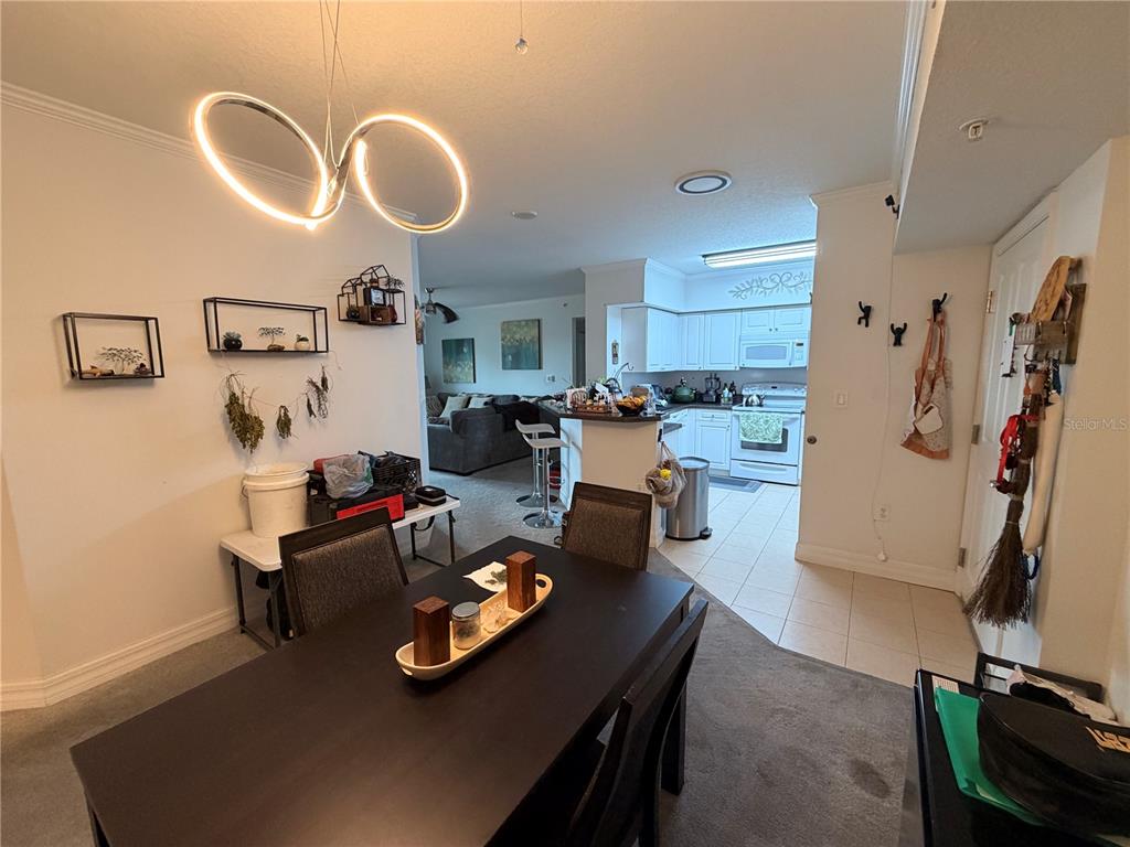 A dining area with a modern light fixture opens into a kitchen and living room — 4516 SEAGULL DRIVE UNIT 515, NEW PORT RICHEY, FL