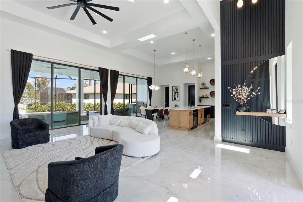 A modern open-concept living and dining area features white tile floors and a dark accent wall — 4218 SW 17TH AVENUE, CAPE CORAL, FL
