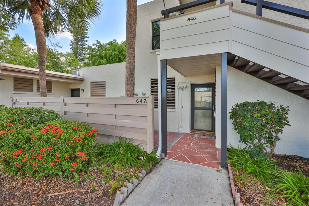 The exterior of a two-story residential building features a ground-level entrance and outdoor stairs — 647 WOODLAWN DRIVE UNIT 647, BRADENTON, FL