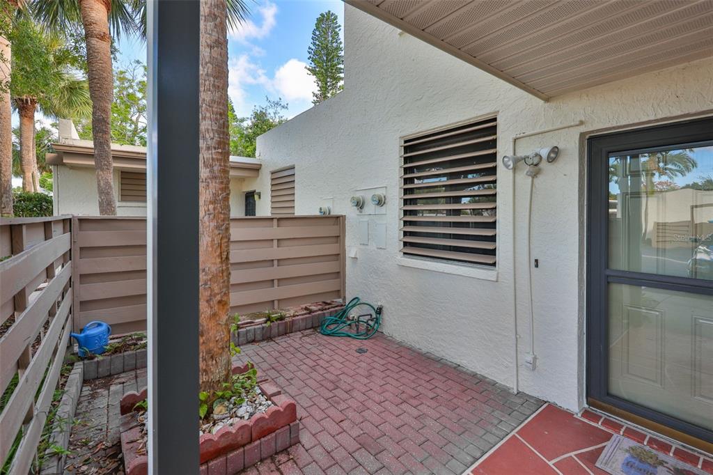 A paved patio area features a brick planter with a tree and a privacy fence — 647 WOODLAWN DRIVE UNIT 647, BRADENTON, FL
