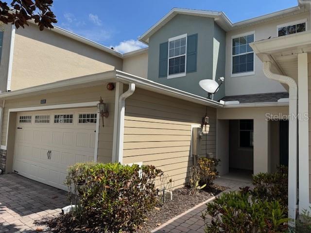 A two-story tan and blue townhouse features a garage and a paved driveway — 1221 PRIORY CIRCLE, WINTER GARDEN, FL