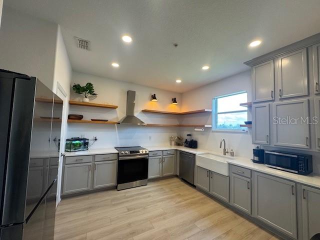 A modern kitchen features gray cabinets, open wood shelving, stainless steel appliances, and light flooring — 1221 PRIORY CIRCLE, WINTER GARDEN, FL