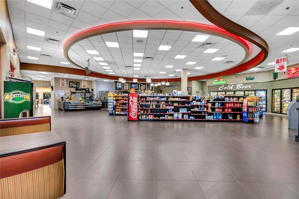 A spacious convenience store interior features tiled floors, drop ceilings, and rows of retail shelving — 5600 BUTLER NATIONAL DRIVE, ORLANDO, FL