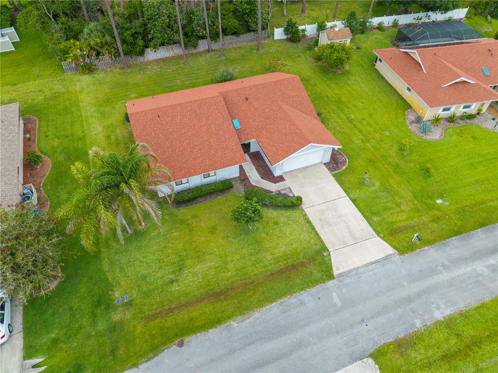 An aerial view shows a single-story house with a red roof, driveway, and lawn — 10 VILLAGE LANE, PALM COAST, FL