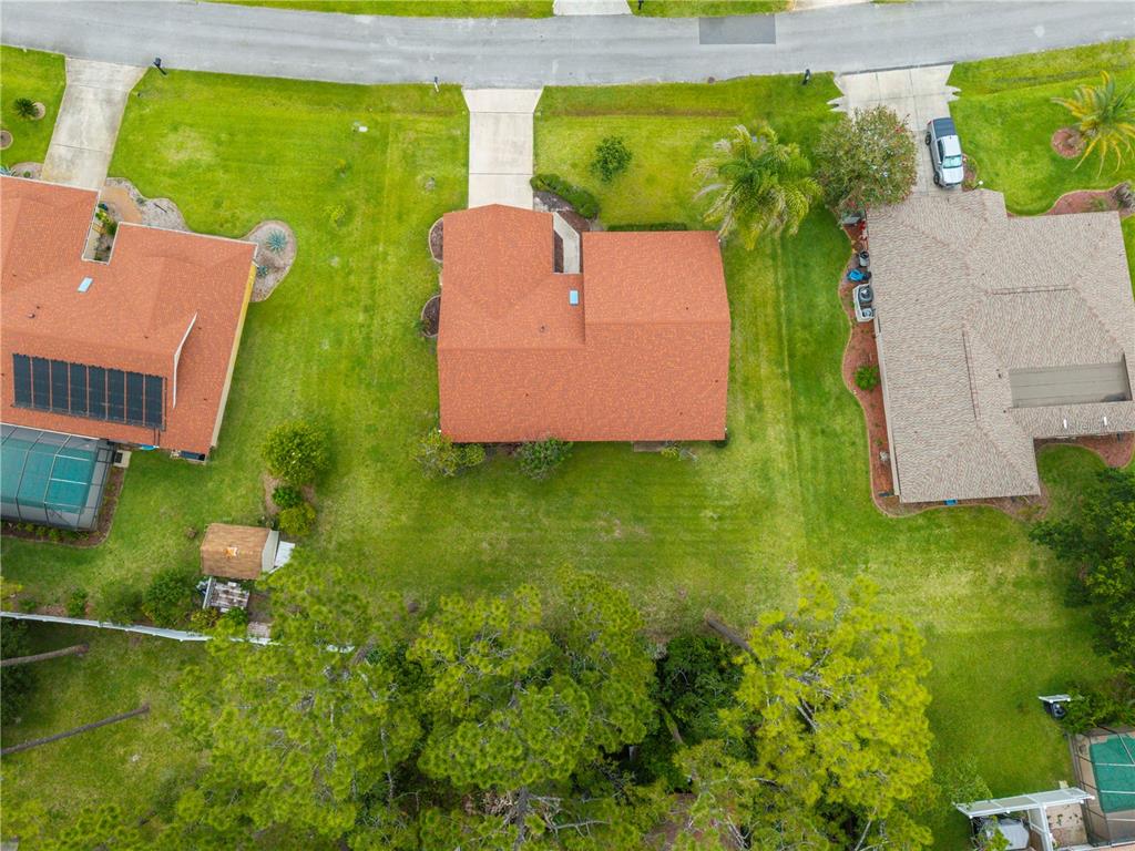 An aerial view shows three suburban houses with orange and gray roofs surrounded by lawns — 10 VILLAGE LANE, PALM COAST, FL