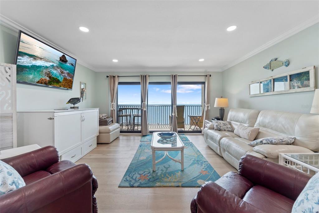 A living room features a white sofa, two maroon armchairs, and a balcony with ocean views — 12924 GULF BOULEVARD UNIT 502, MADEIRA BEACH, FL