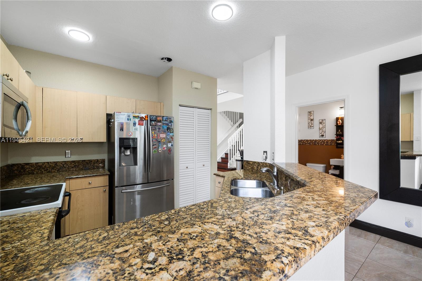 A kitchen features light wood cabinets, granite countertops, stainless steel appliances, and a breakfast bar — 1199 Golden Cane Dr, Weston FL 33327, WESTON, FL