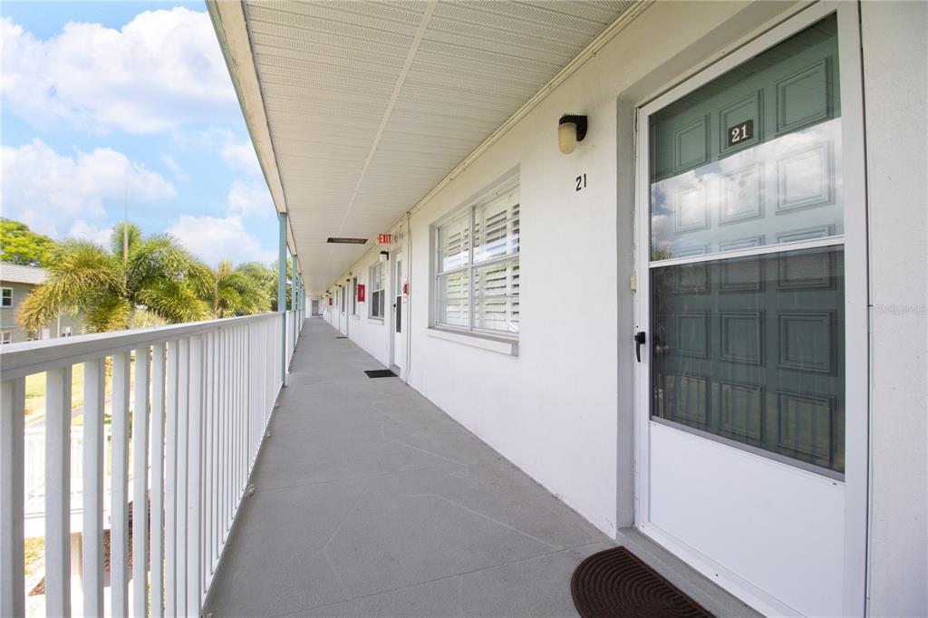 An exterior walkway with white railings leads past apartment doors and windows under a roof — 5267 81ST STREET N UNIT 21, ST PETERSBURG, FL