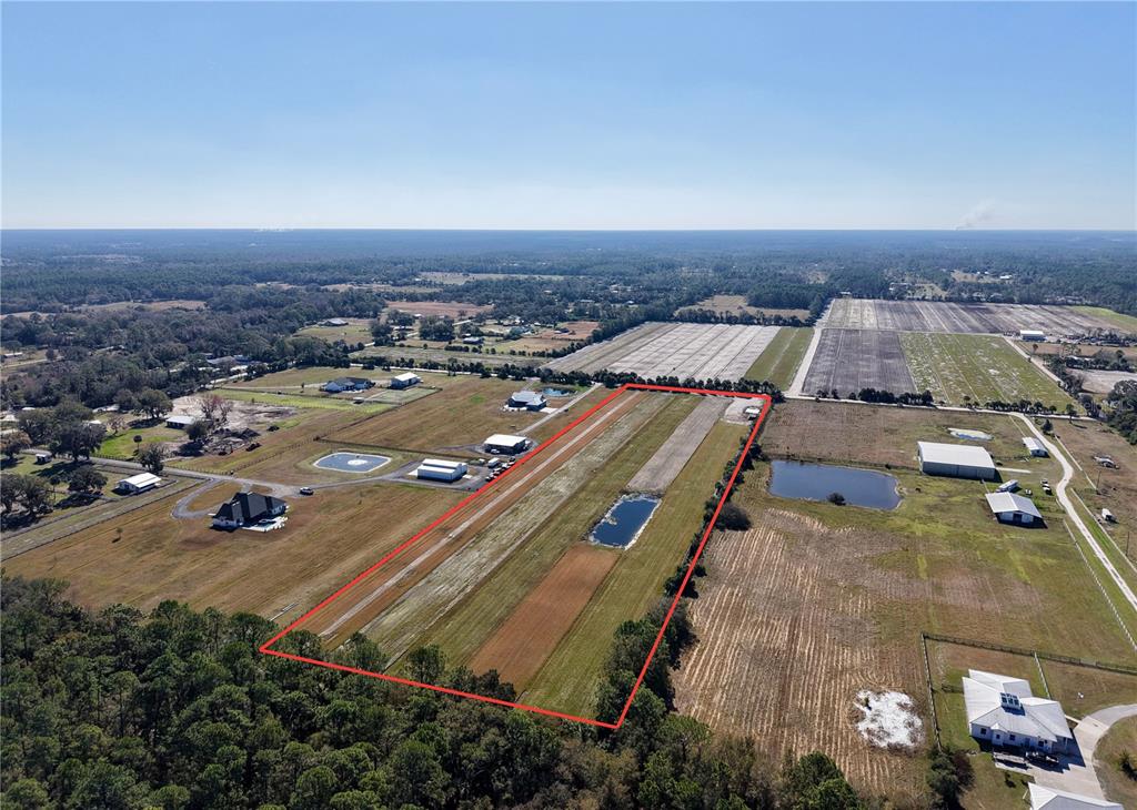 An aerial view shows a rectangular plot of land outlined in red featuring a runway — 3761 STRAWBERRY LANE, NEW SMYRNA BEACH, FL