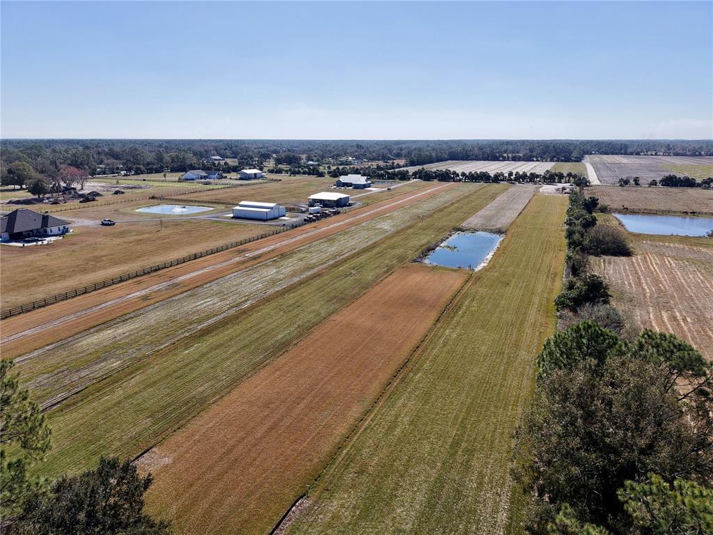An aerial view shows a large, flat rural property with several buildings and small ponds — 3761 STRAWBERRY LANE, NEW SMYRNA BEACH, FL