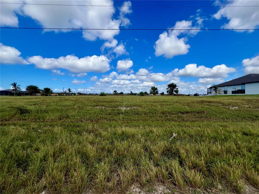 A vacant, grassy lot under a bright blue sky with scattered clouds — 4103 NW 39TH STREET, CAPE CORAL, FL