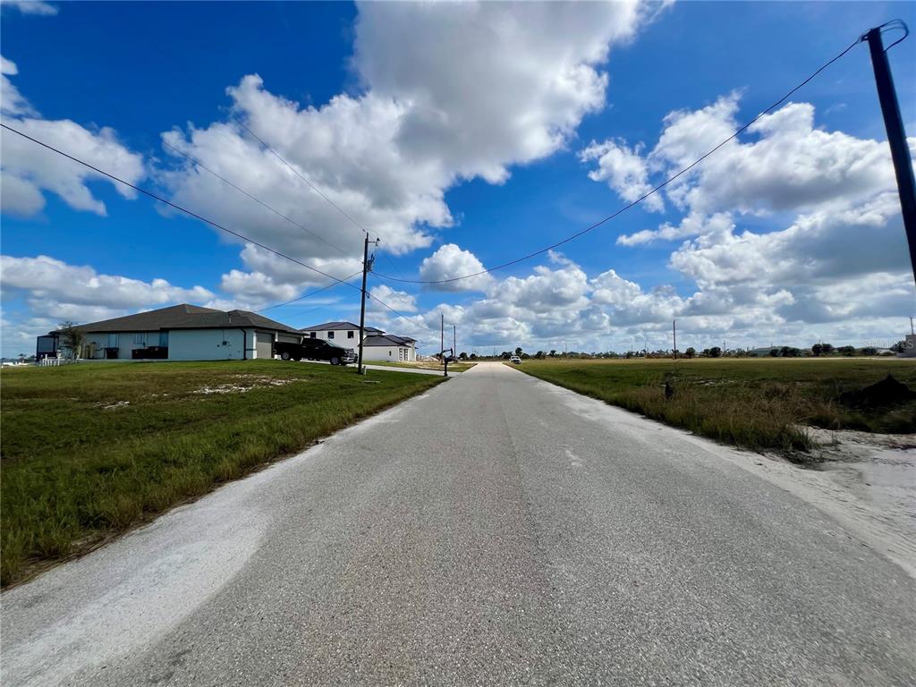 A paved road stretches between a residential house on the left and an empty lot — 4103 NW 39TH STREET, CAPE CORAL, FL
