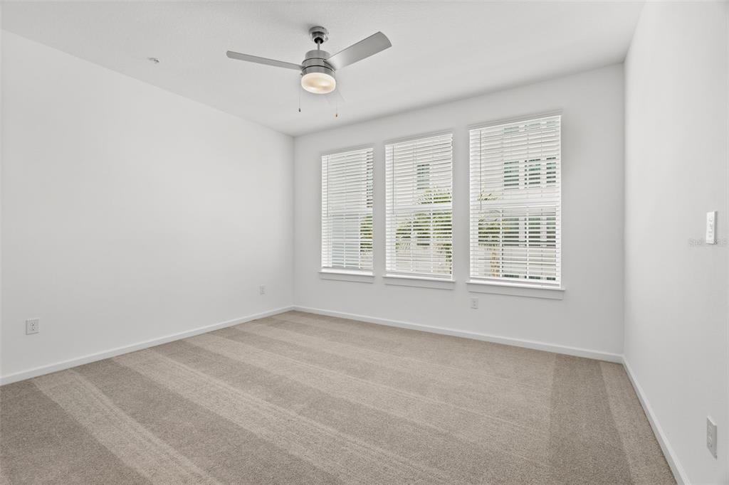 An empty bedroom with white walls, beige carpet, a ceiling fan, and three windows — 1700 RANCH ROAD UNIT B3-6215, NOKOMIS, FL